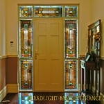 Formal entry with suround in coloured glass with some painted details of leaves in a geometric setting.