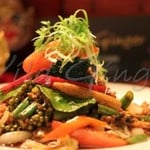 a bed of thai rice stick noodles stir-fried with egg topped with chicken mince stir-fry with vegetables in thai sauce